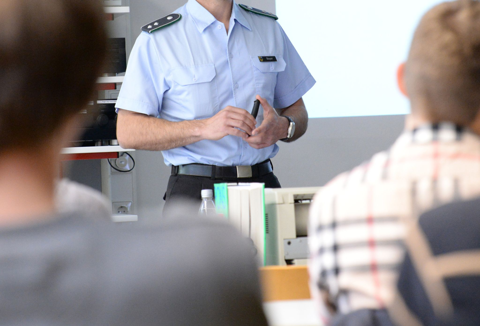 Ein Oberleutnant spricht in einem Gymnasium vor einer Klasse und stellt die Arbeit der Bundeswehr vor.