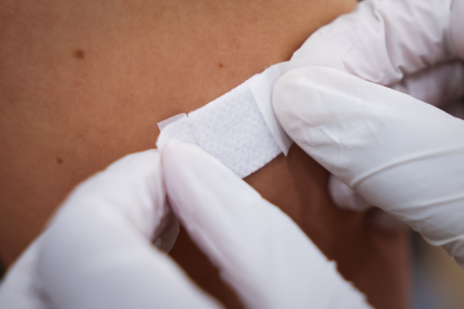 Eine Ärztin klebt einem Mann nach der Impfung ein Pflaster auf den Arm.