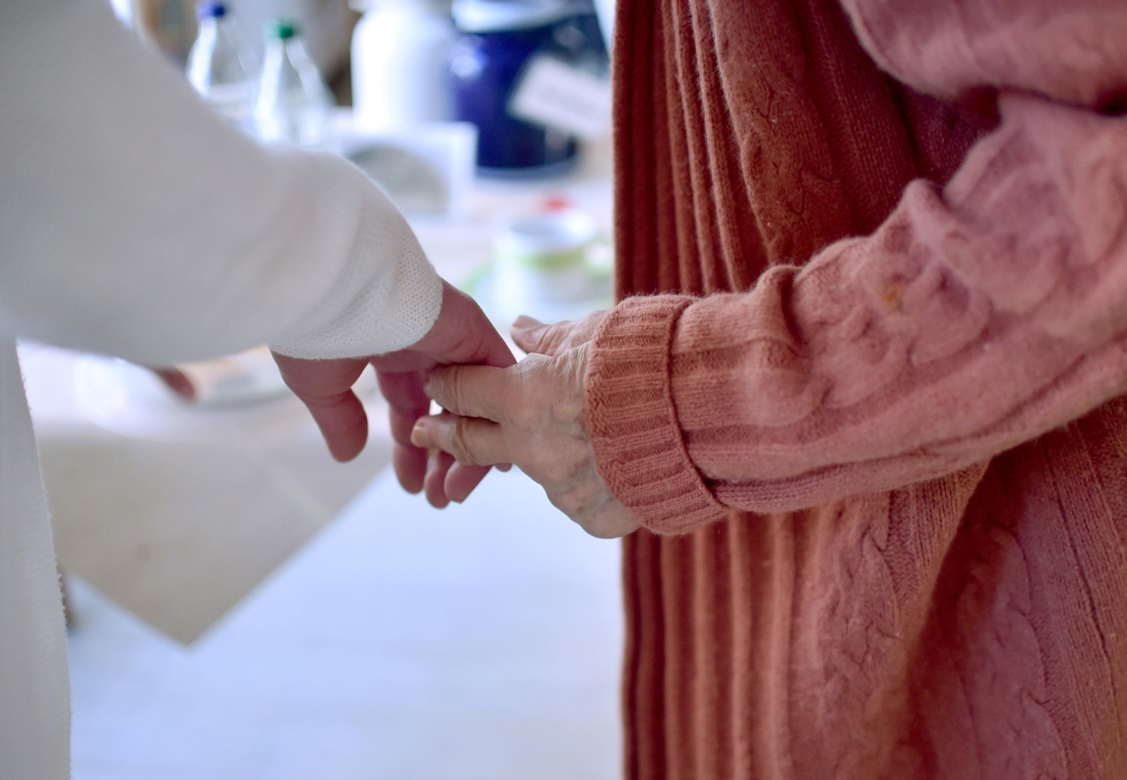 Eine Pflegekraft hält die Hand einer Bewohnerin einer Pflegeeinrichtung.