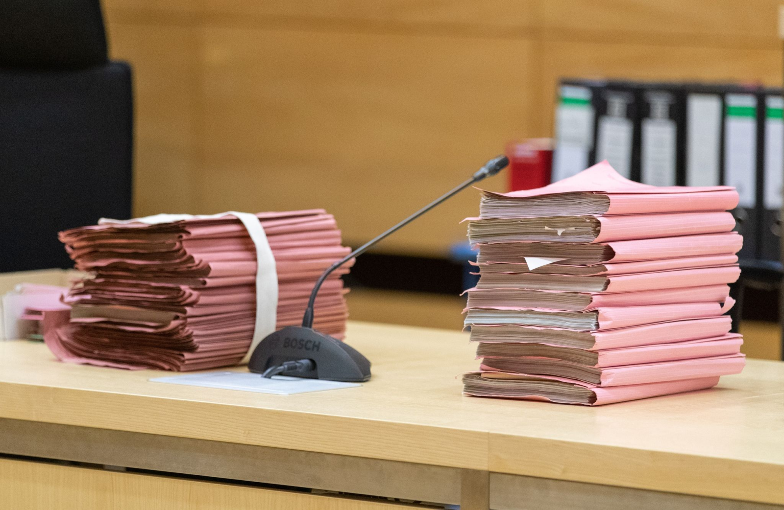 Prozessakten liegen in einem Gerichtssaal auf dem Tisch.
