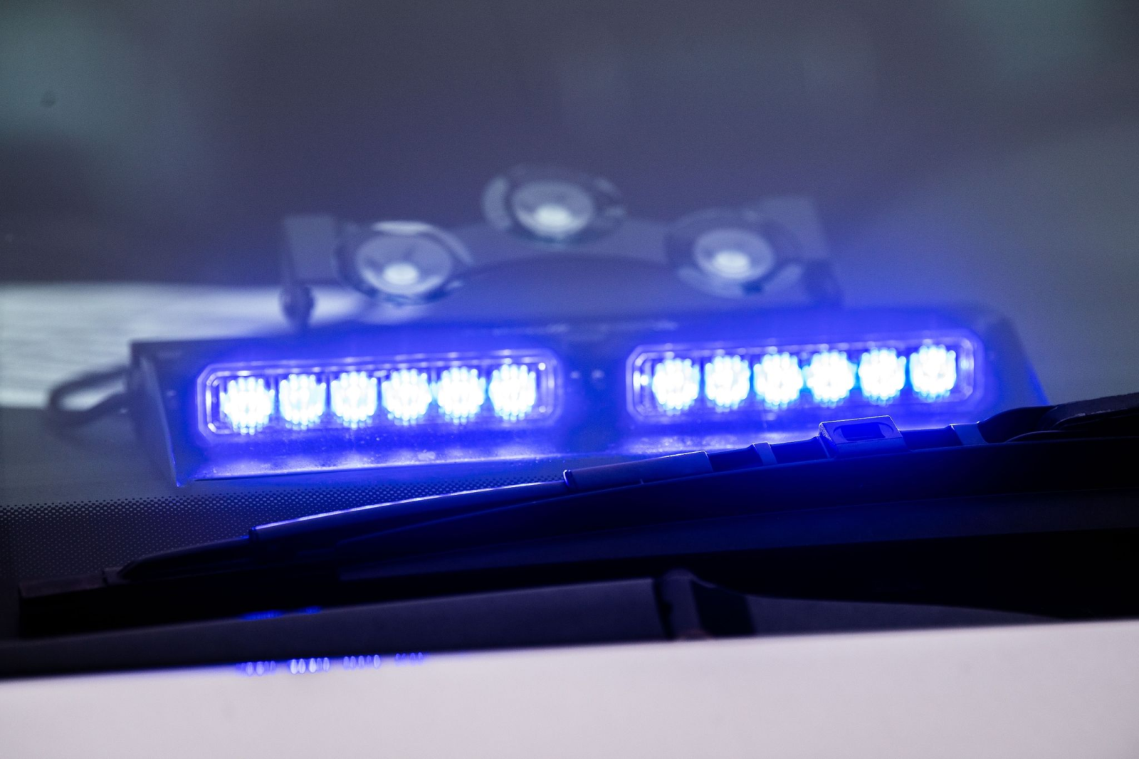 Ein Blaulicht leuchtet unter der Frontscheibe eines Einsatzfahrzeugs der Polizei., © Lino Mirgeler/dpa/Symbolbild