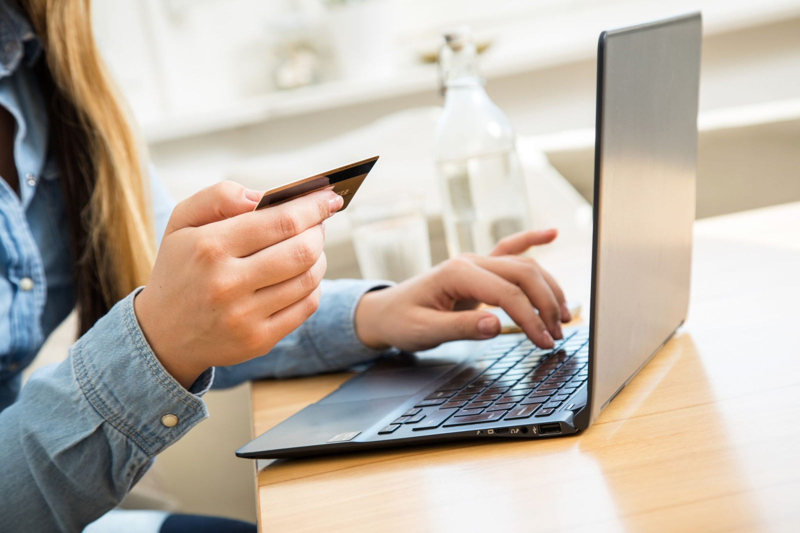 Eine Frau tippt ihre Kreditkarten-Daten in einen Laptop.