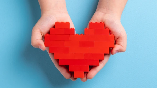 Kinderhände halten Herz aus Lego, © Shutterstock Kinderhände halten Herz aus Lego, © Shutterstock