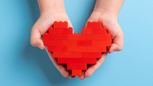 Kinderhände halten Herz aus Lego, © Shutterstock