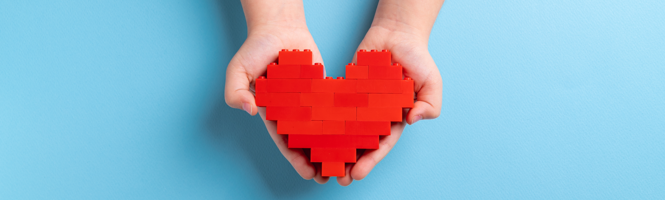 Kinderhände halten Herz aus Lego, © Shutterstock
