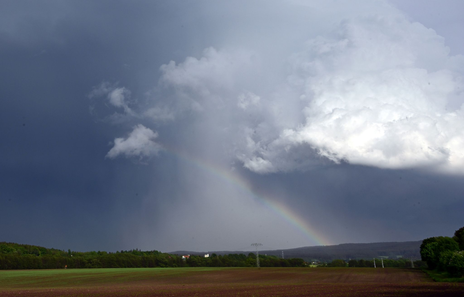 Ein Regenbogen bildet sich vor dunklen Wolken bei Langewiesen.