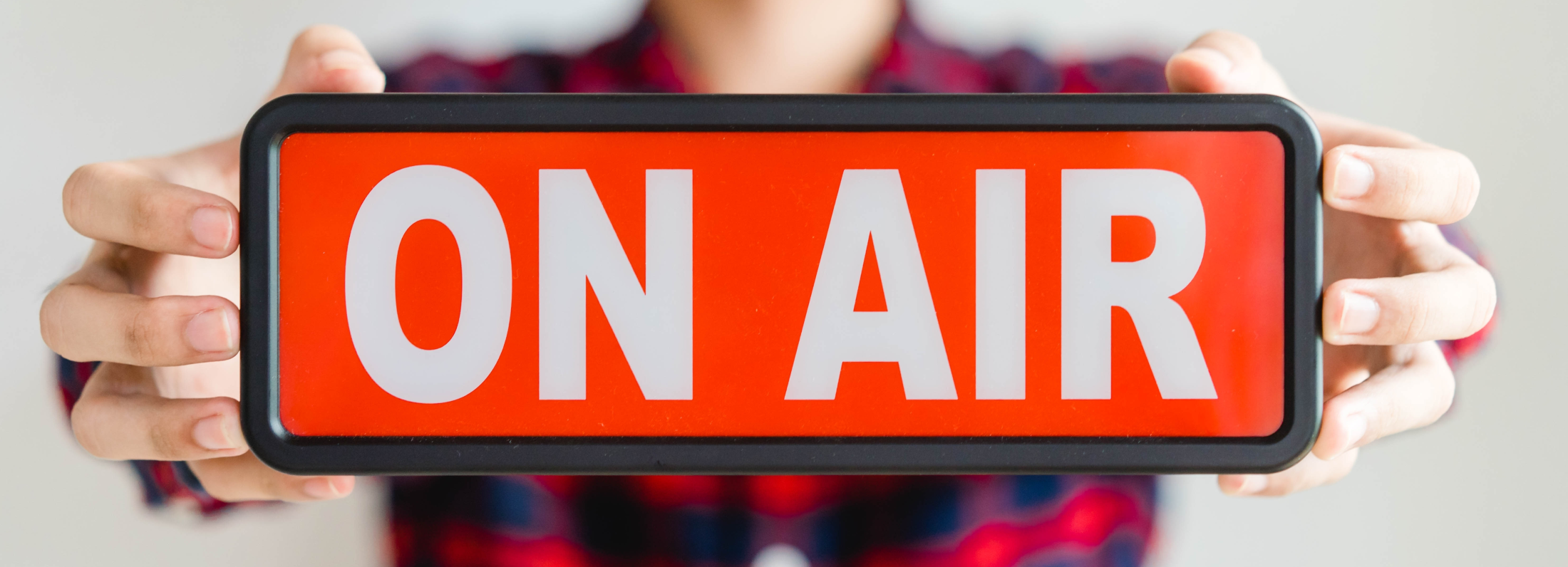 Mann hält ein On Air Schild in den Händen, © Shutterstock
