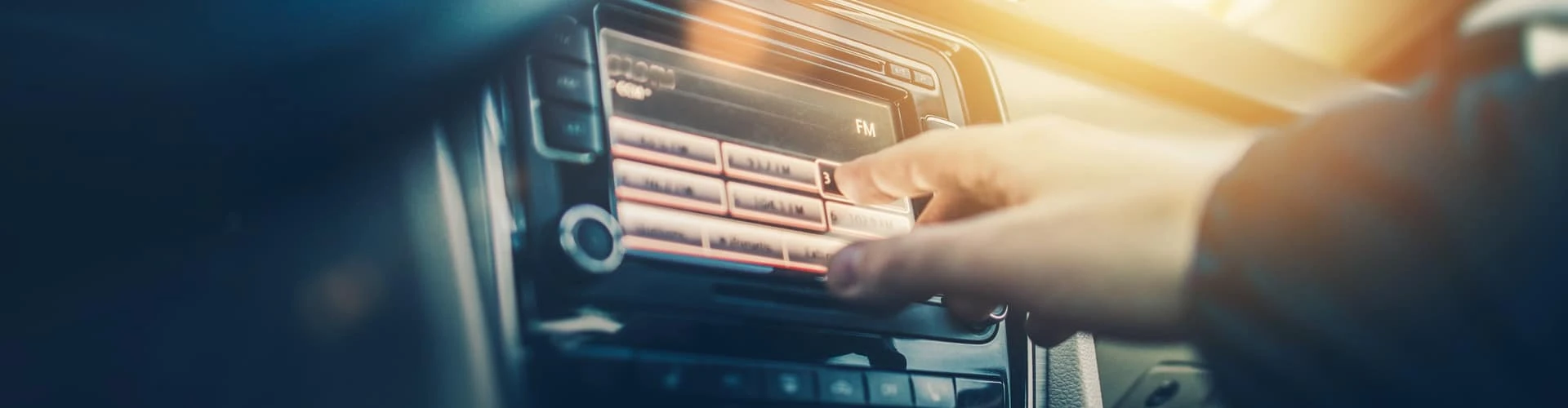 Eine Person bedient das Autoradio, © Shutterstock Eine Person bedient das Autoradio, © Shutterstock