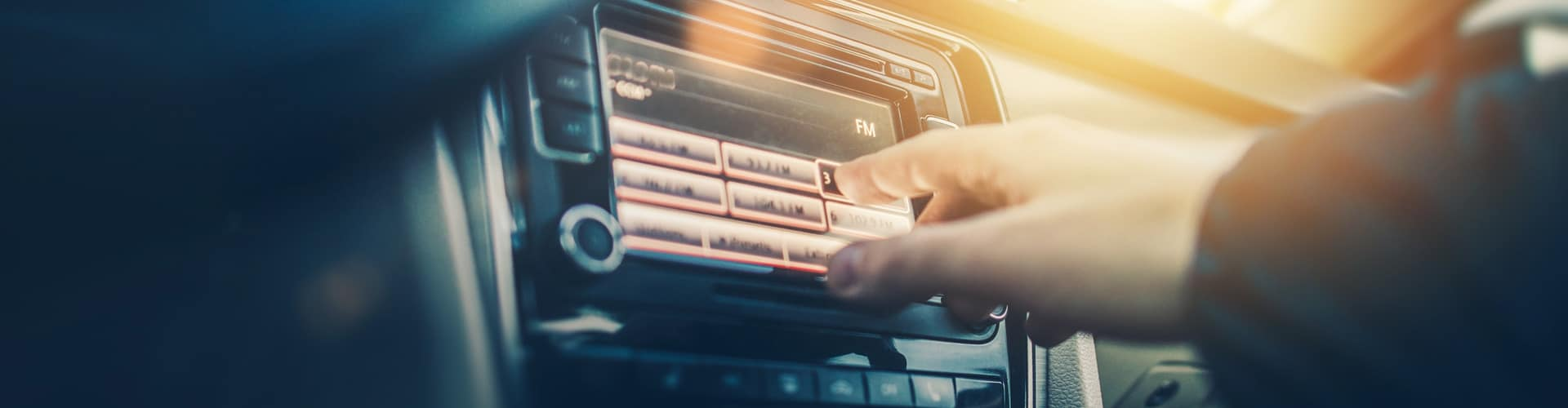 Eine Person bedient das Autoradio, © Shutterstock