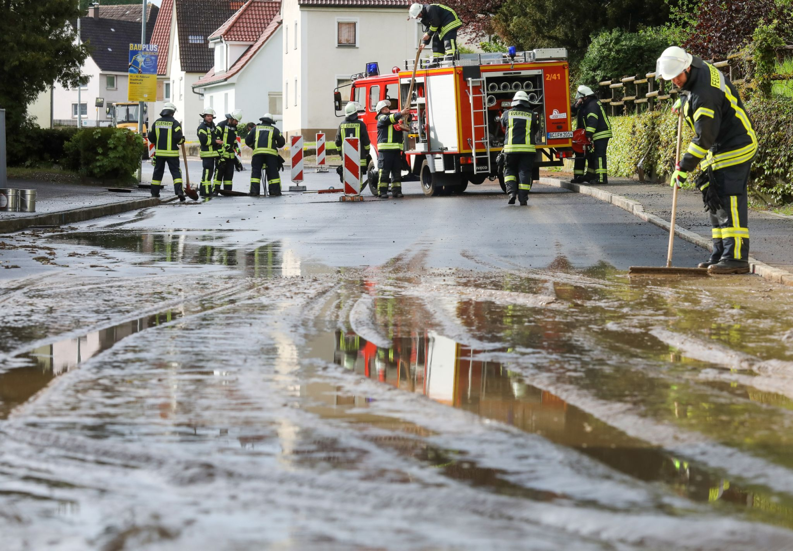 Einsatzkräfte der Feuerwehr reinigen eine überflutete und verschmutzte Straße., © Thomas Warnack/dpa/Symbolbild