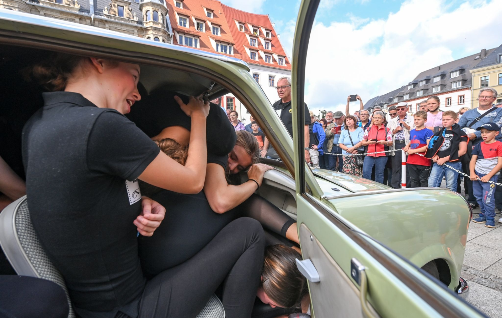 Auf dem Zwickauer Hauptmarkt zwängen sich im September 2021 junge Sportlerinnen in einen Trabant.