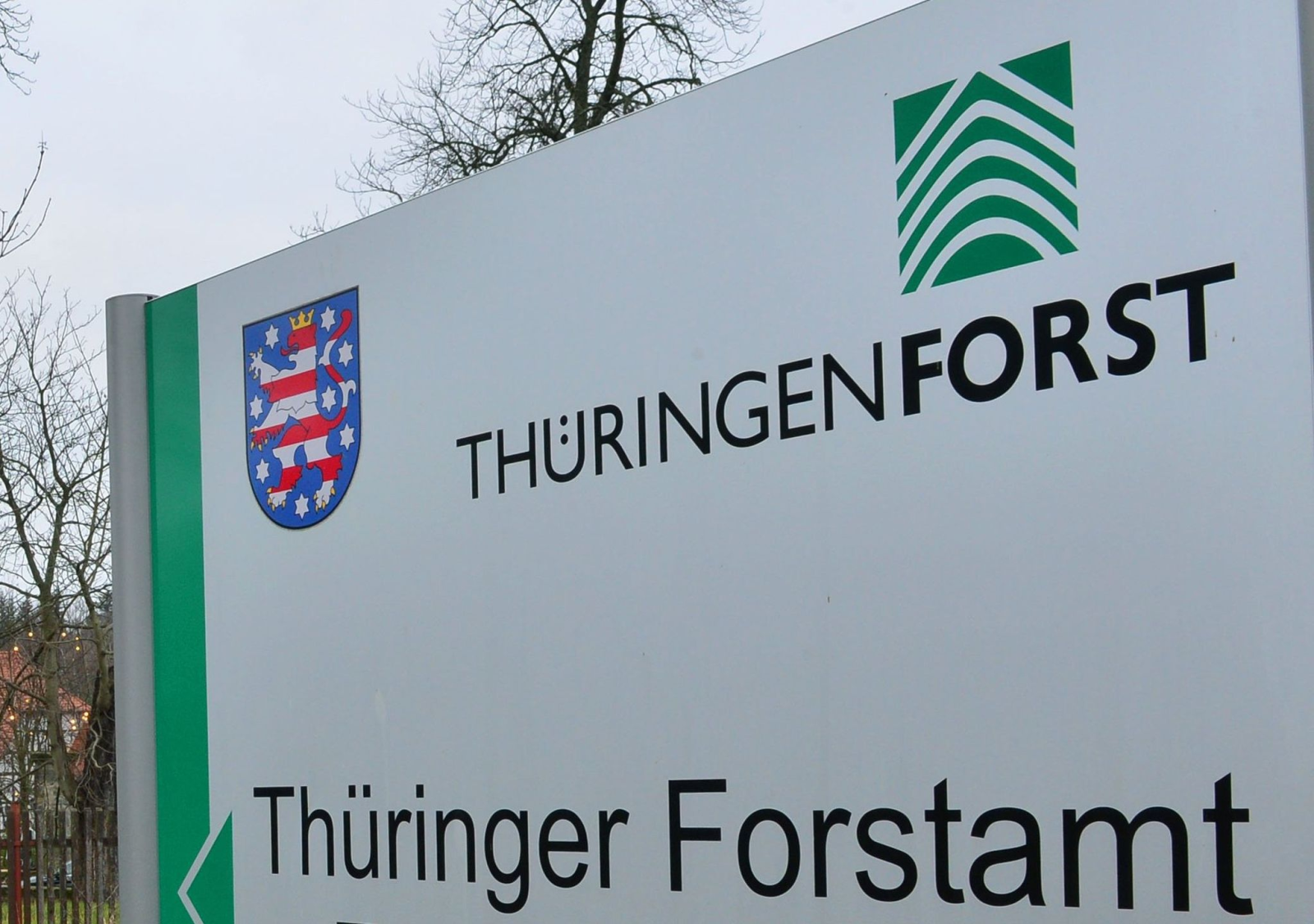 Eine Tafel des Thüringer Forstamtes steht vor einem Forsthaus.
