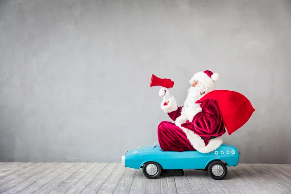Weihnachtsmann mit Sack im Spielzeugauto, © Shutterstock Weihnachtsmann mit Sack im Spielzeugauto, © Shutterstock