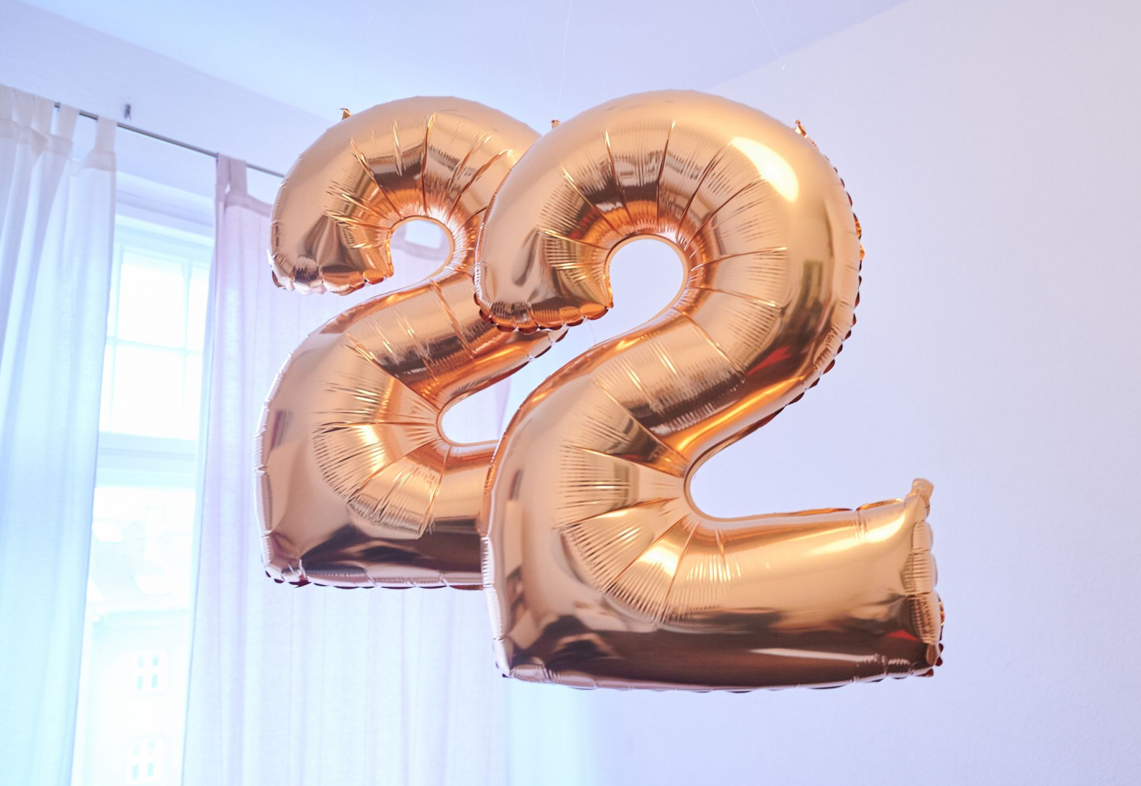 Zwei goldene Luftballons in Form der Zahl «Zwei» hängen von einer Decke.