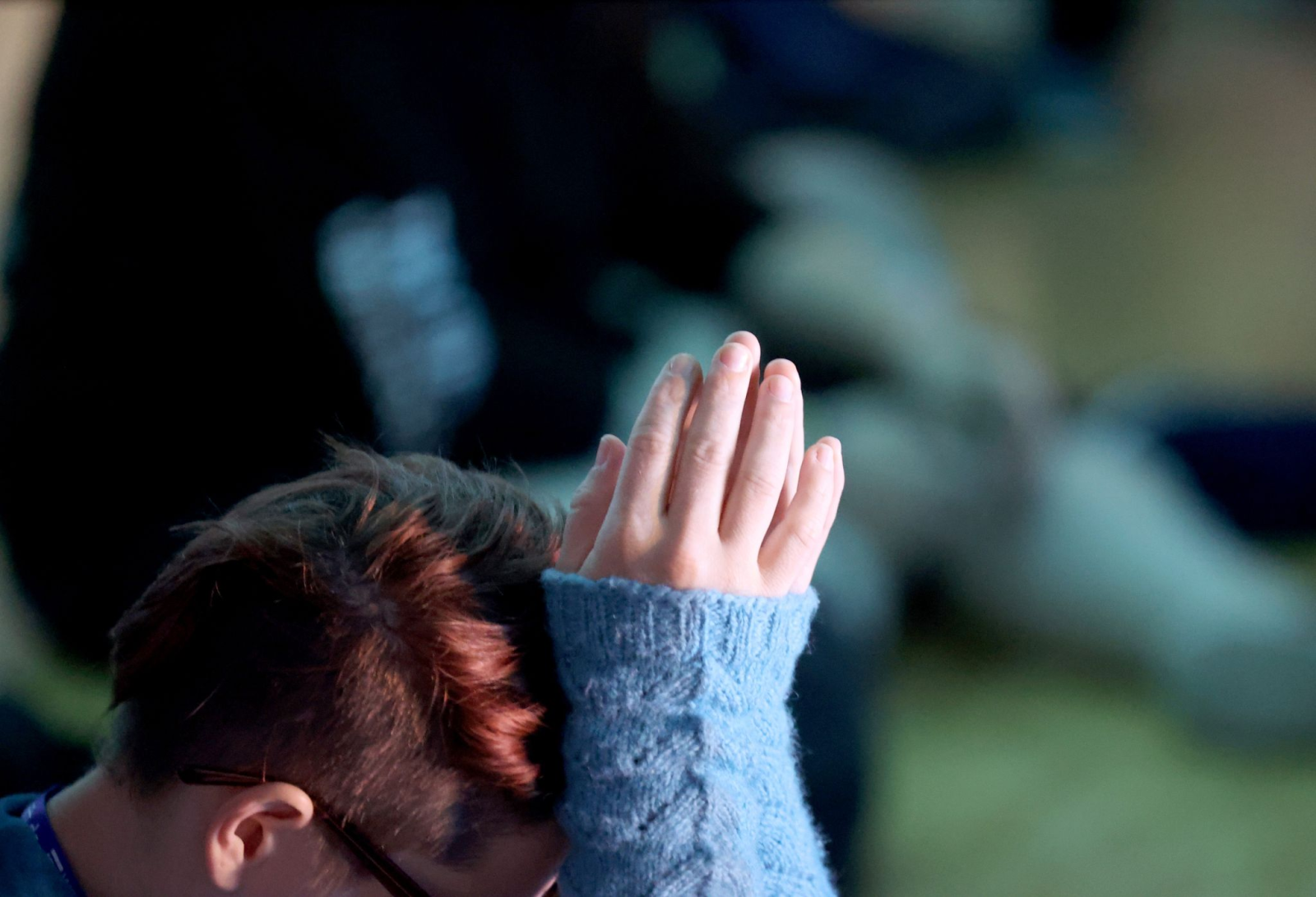 Eine Teilnehmerin hält beim Abschlussgottesdienst in der Messehalle die Hände gefaltet.