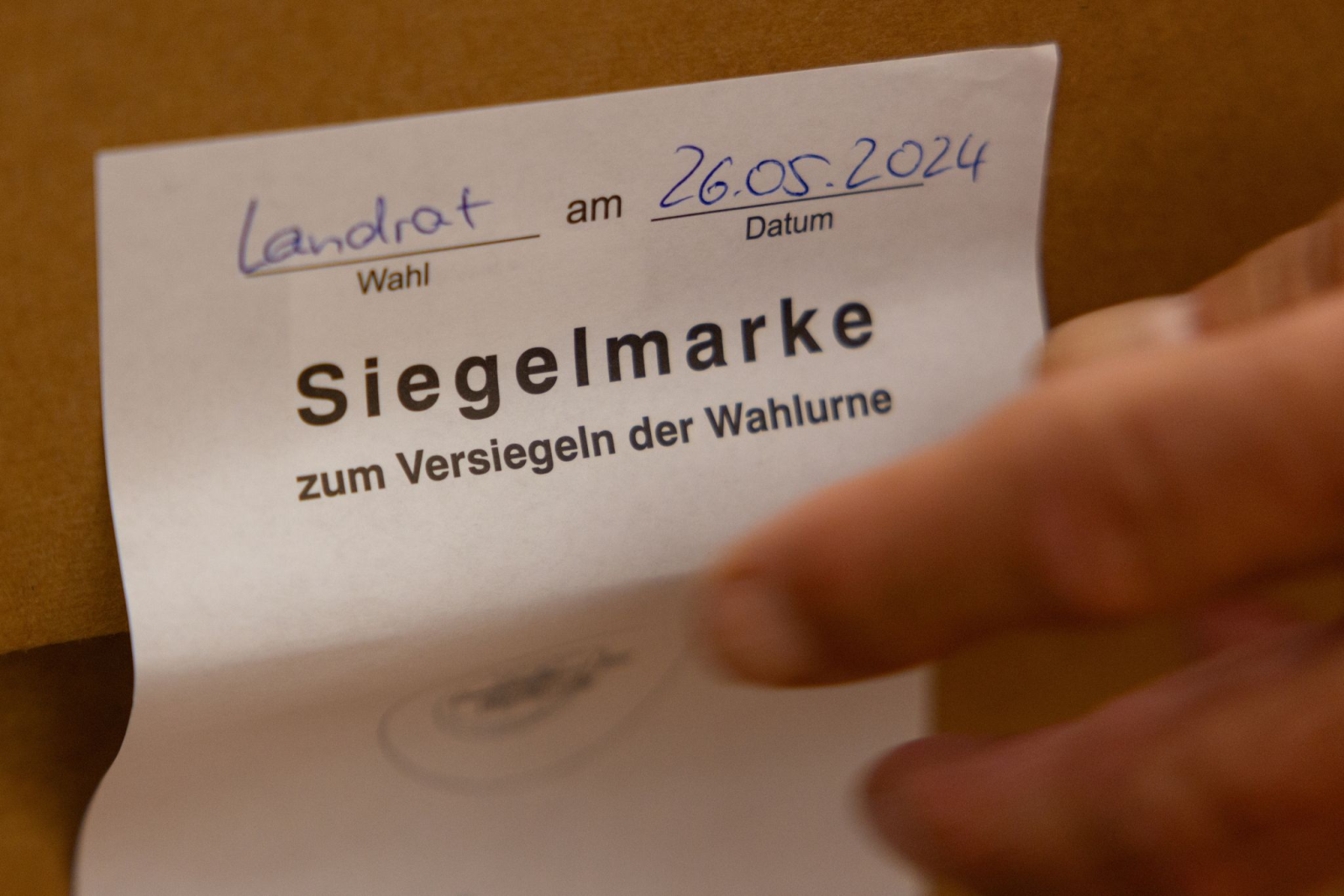 Ein Wahlhelfer entfernt die Siegelmarke einer Wahlurne zur Auszählung der Stimmzettel., © Michael Reichel/dpa