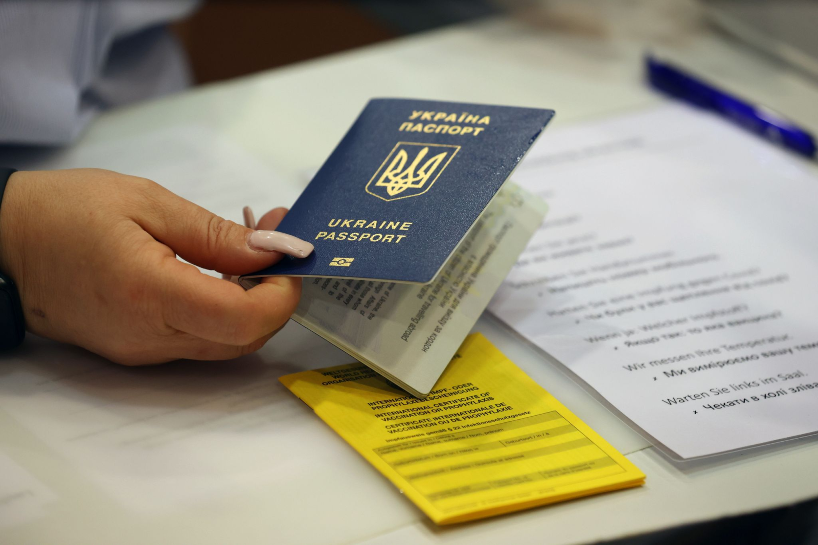 Eine Mitarbeiterin hält einen Reisepass aus der Ukraine im Anmeldebereich für eine Sonderimpfaktion.