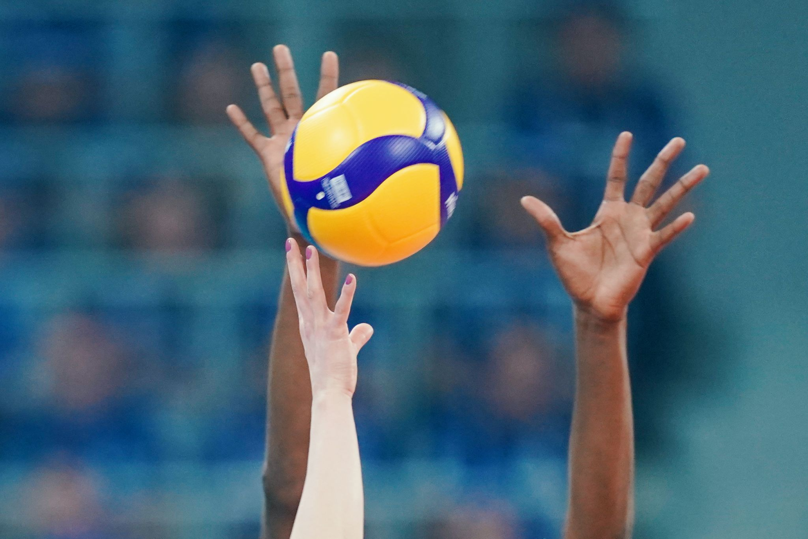 Spielerinnen strecken ihre Arme in Richtung eines Volleyballs.