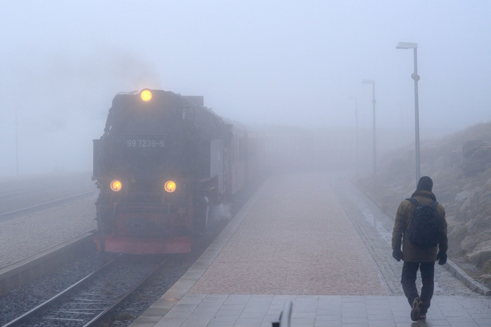 Die Brockenbahn der Harzer Schmalspurbahnen (HSB) fährt bei dichtem Nebel in einen Bahnhof ein.