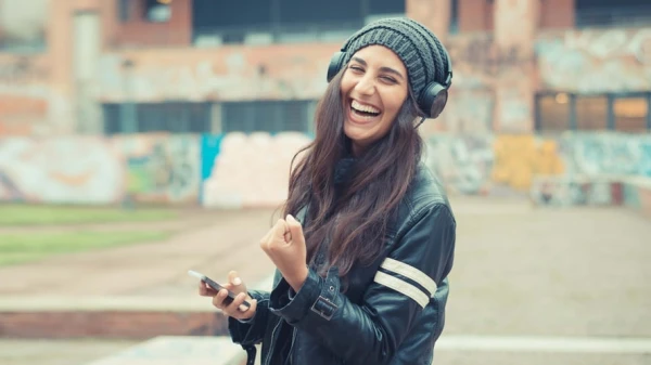 Frau mit Kopfhörern freut sich und hat ihre Hand zu einer Faust gemacht, © Shutterstock Frau mit Kopfhörern freut sich und hat ihre Hand zu einer Faust gemacht, © Shutterstock