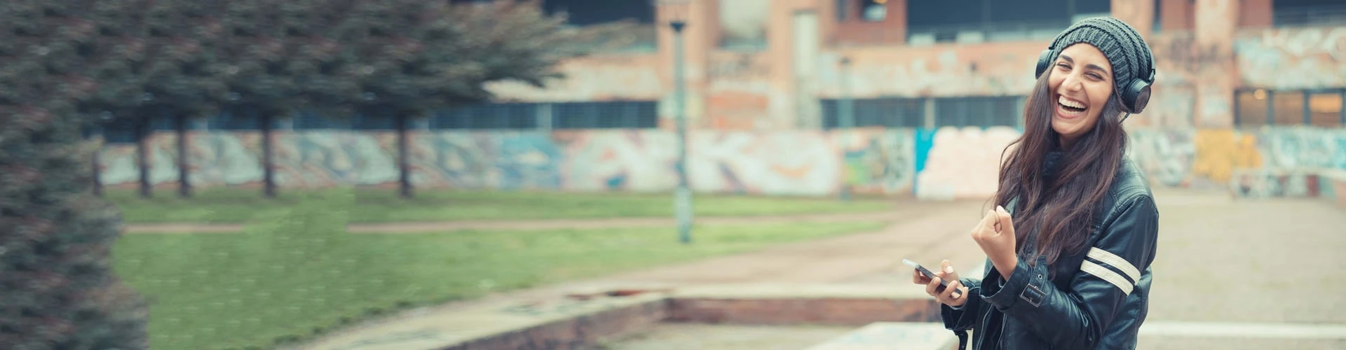 Frau mit Kopfhörern freut sich und hat ihre Hand zu einer Faust gemacht, © Shutterstock Frau mit Kopfhörern freut sich und hat ihre Hand zu einer Faust gemacht, © Shutterstock