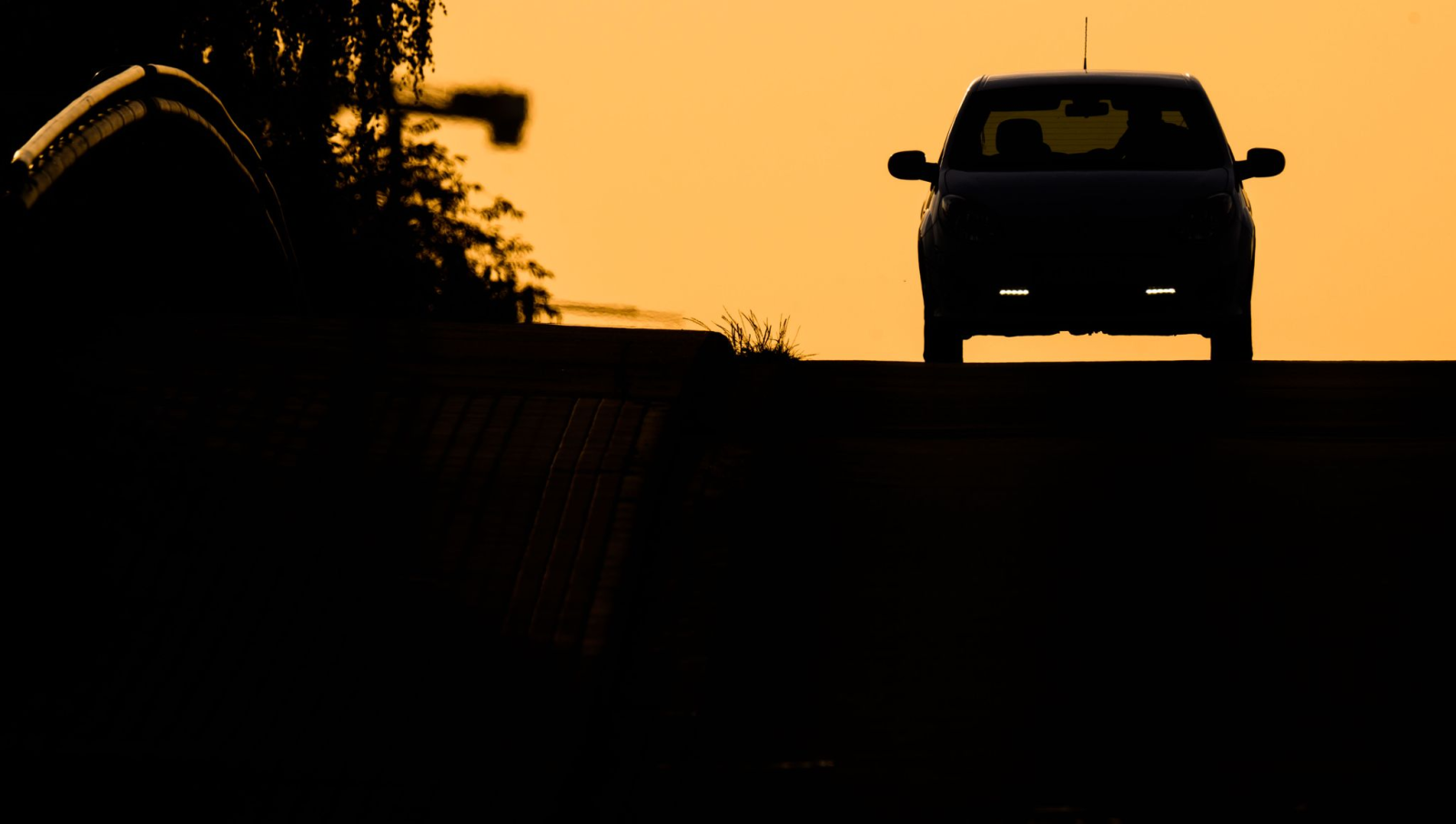 Ein Auto fährt bei Sonnenaufgang über eine Brücke.