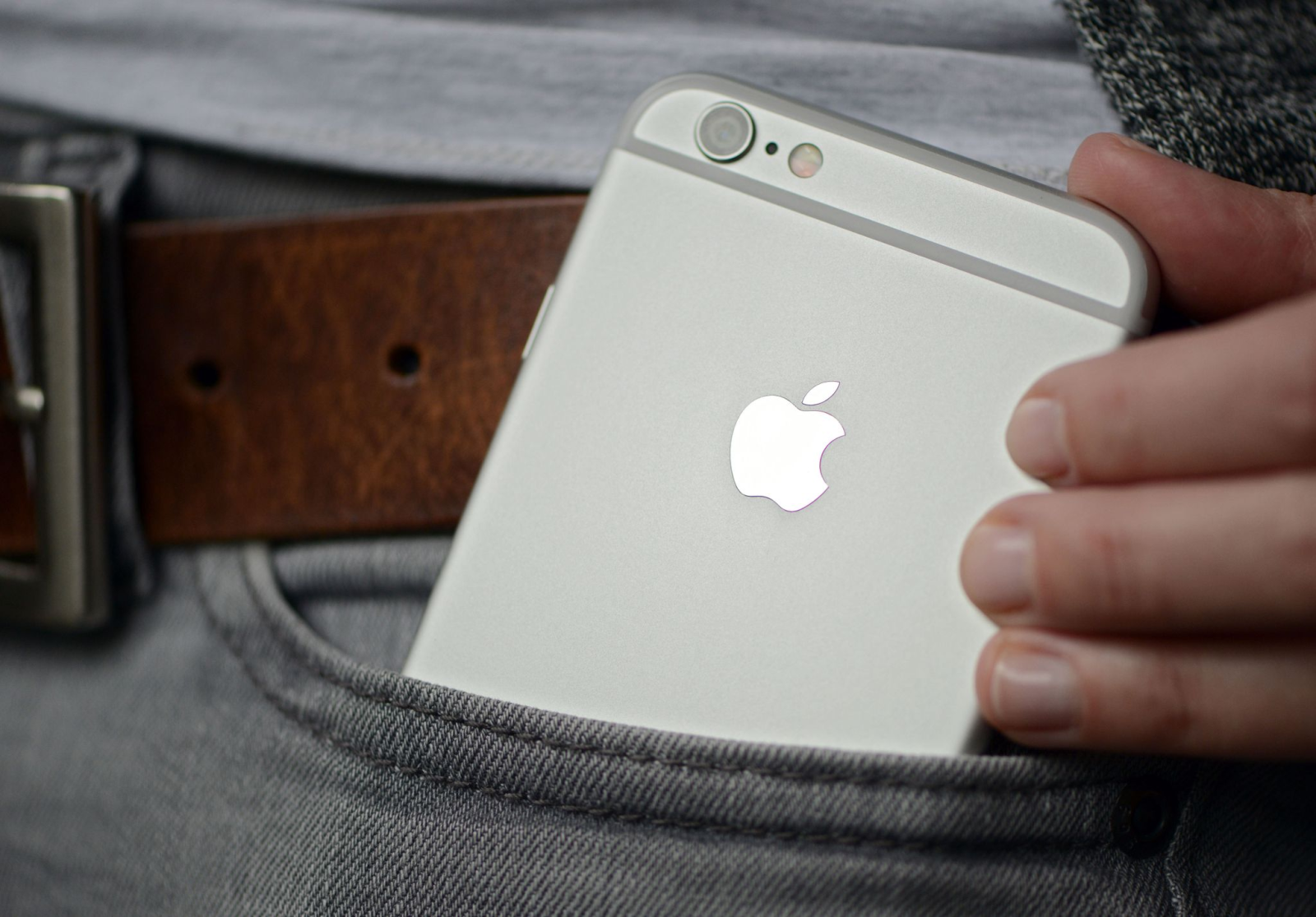 Eine Frau steckt sich ein iPhone der Firma Apple in die Hosentasche.