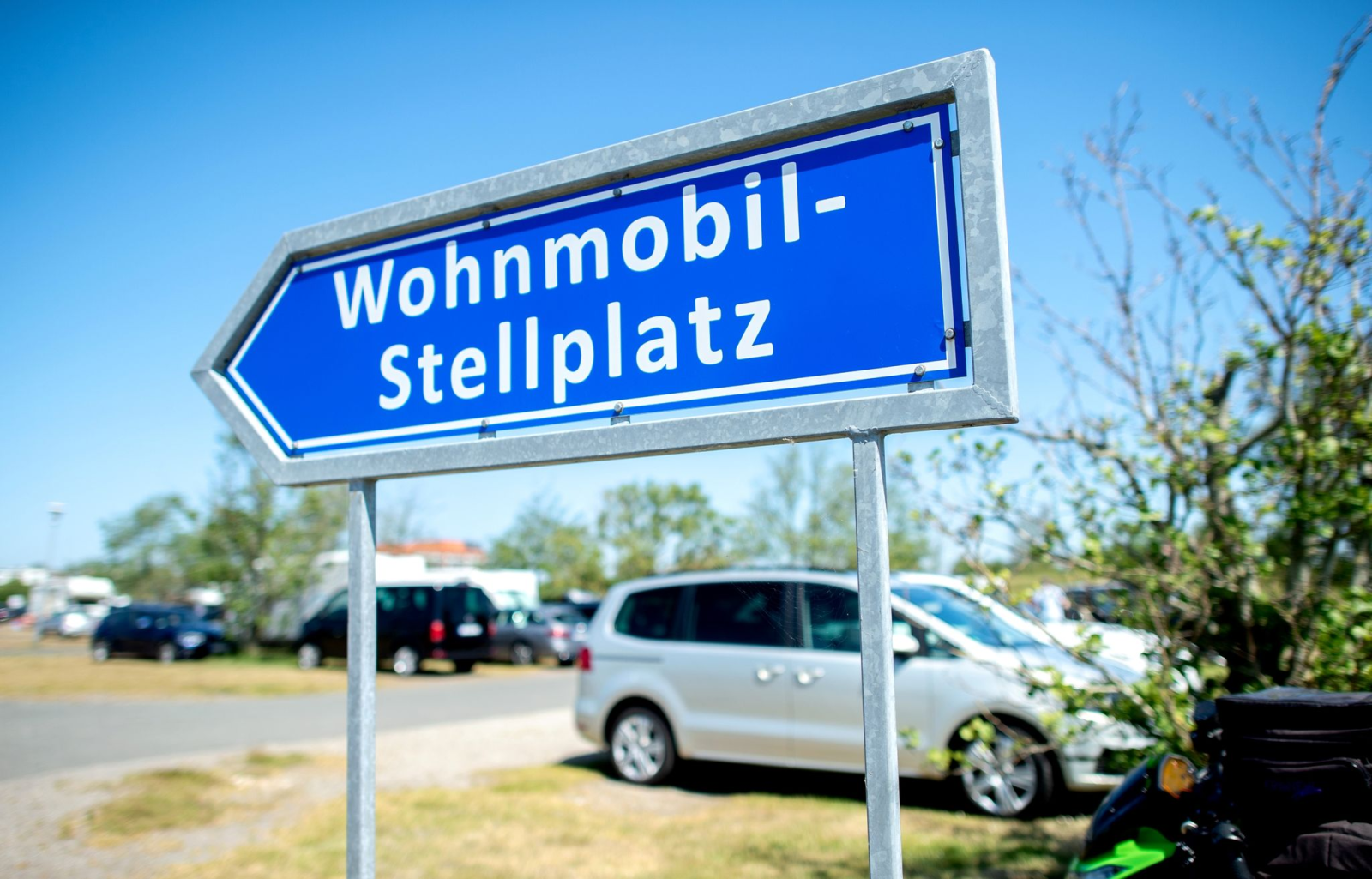 Ein Schild mit der Aufschrift „Wohnmobil-Stellplatz“ steht auf einem Parkplatz.
