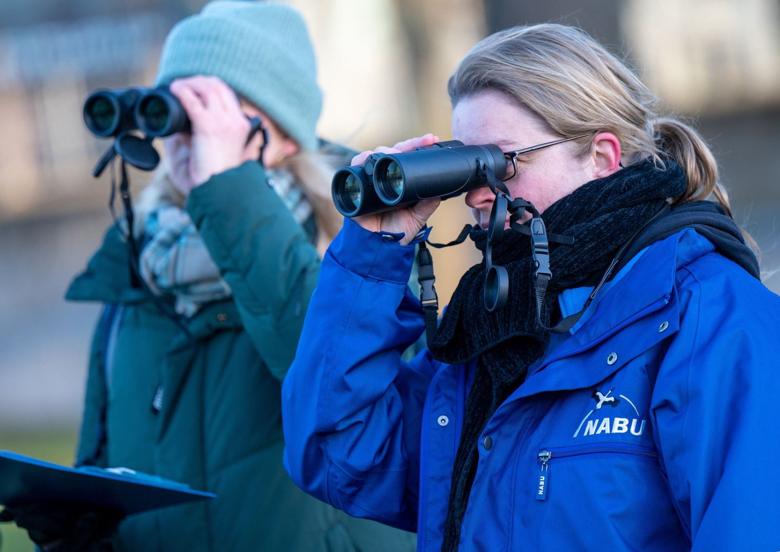 Zwei Teilnehmerinnen der Vogelzählung beobachten mit Ferngläsern die Vögel in einem Park in Berlin.