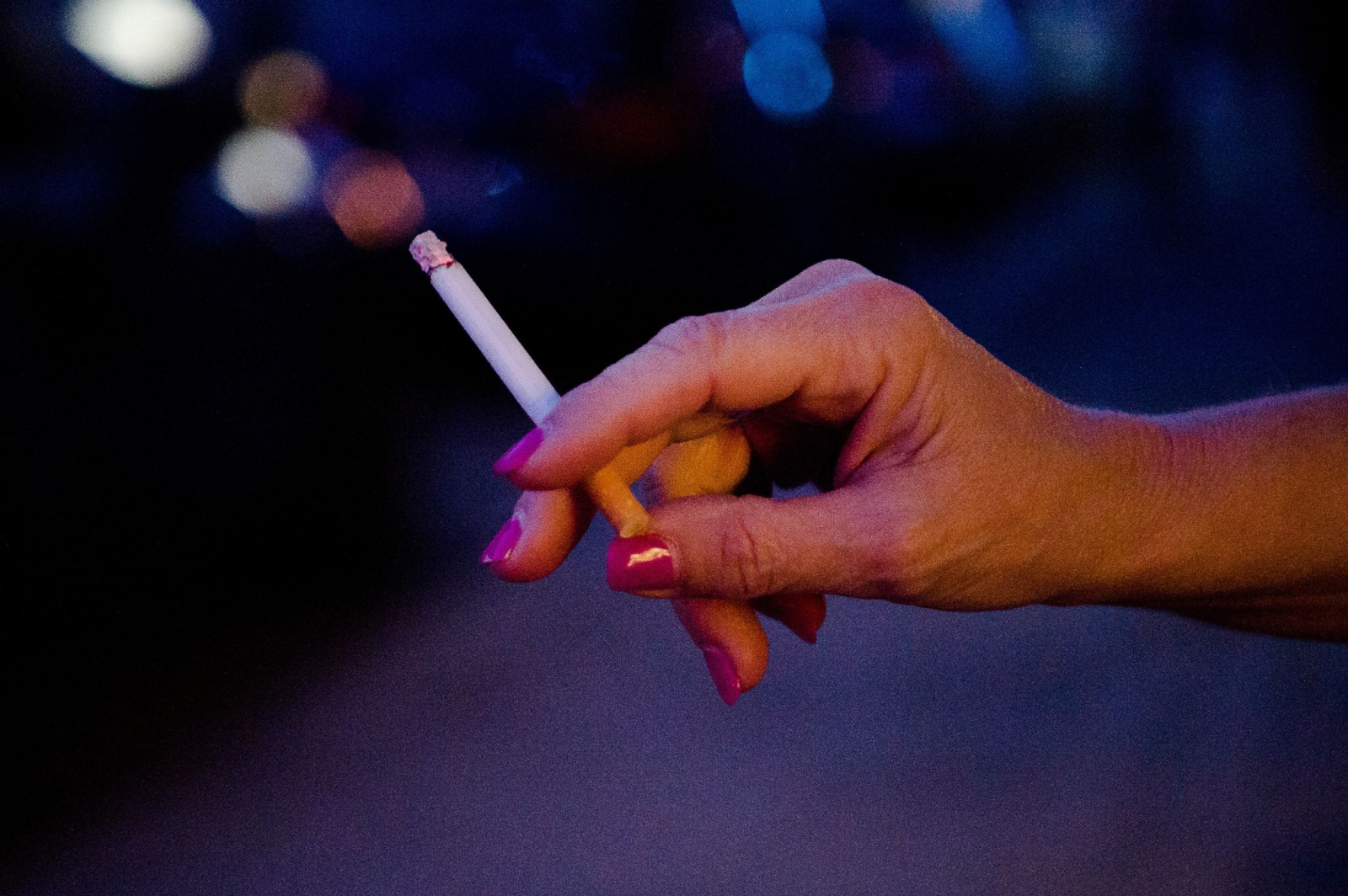 Eine Frau steht auf einer Straße und hält eine Zigarette in der Hand.