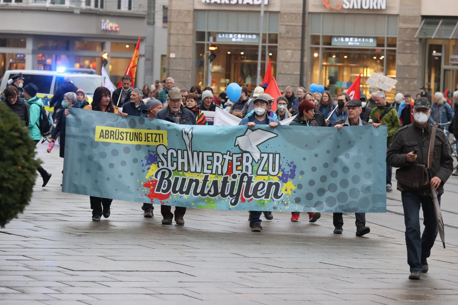 Teilnehmer eines Ostermarsches laufen mit Plakaten auf dem Anger.