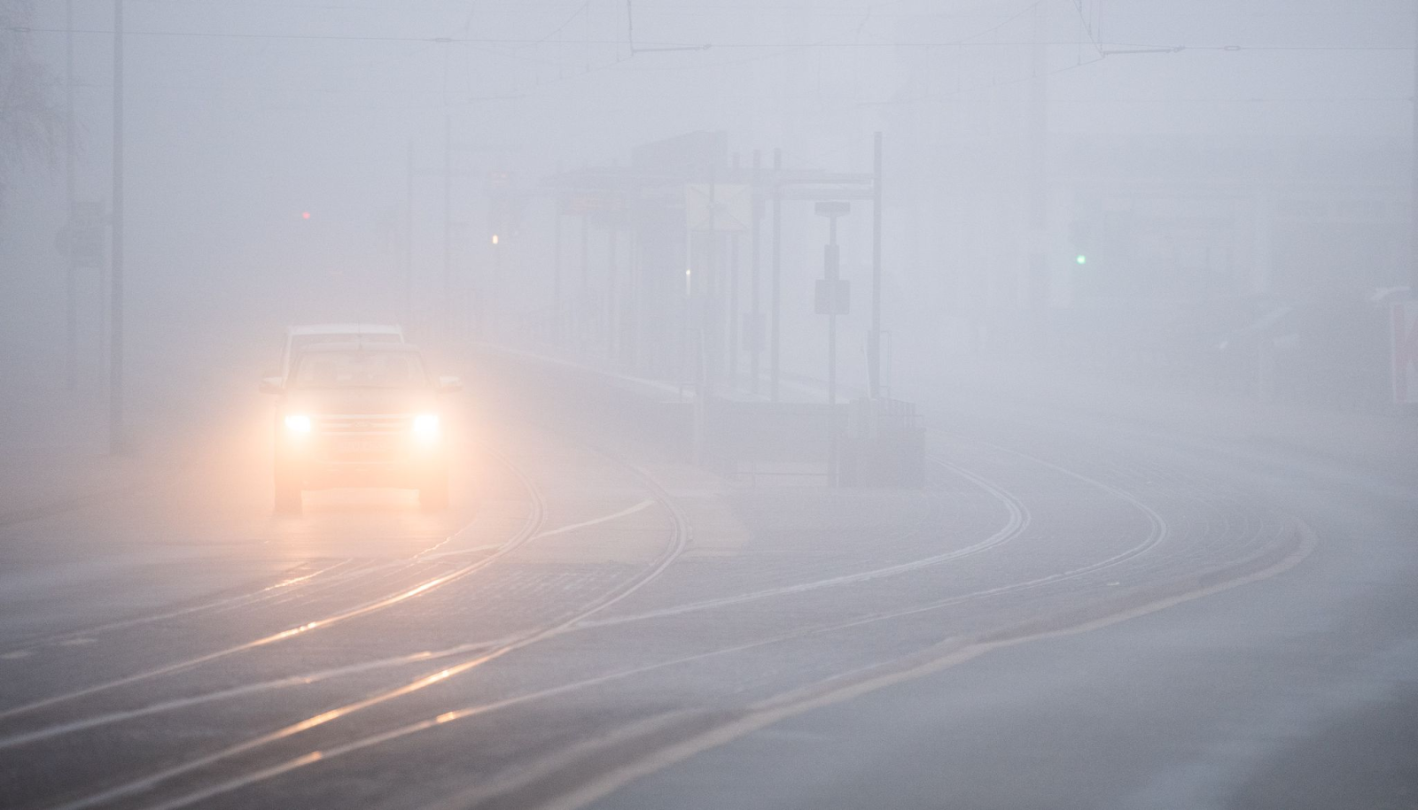 Autos fahren bei dichtem Nebel über eine Straße.