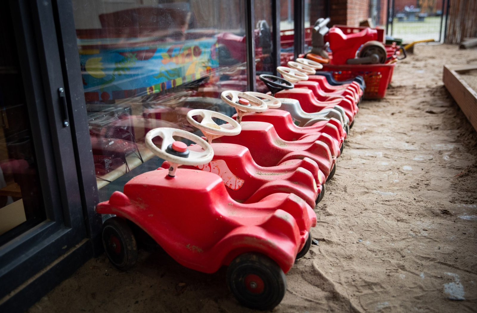 Mehrere Bobbycars stehen auf dem Spielplatz eines Kindergartens.