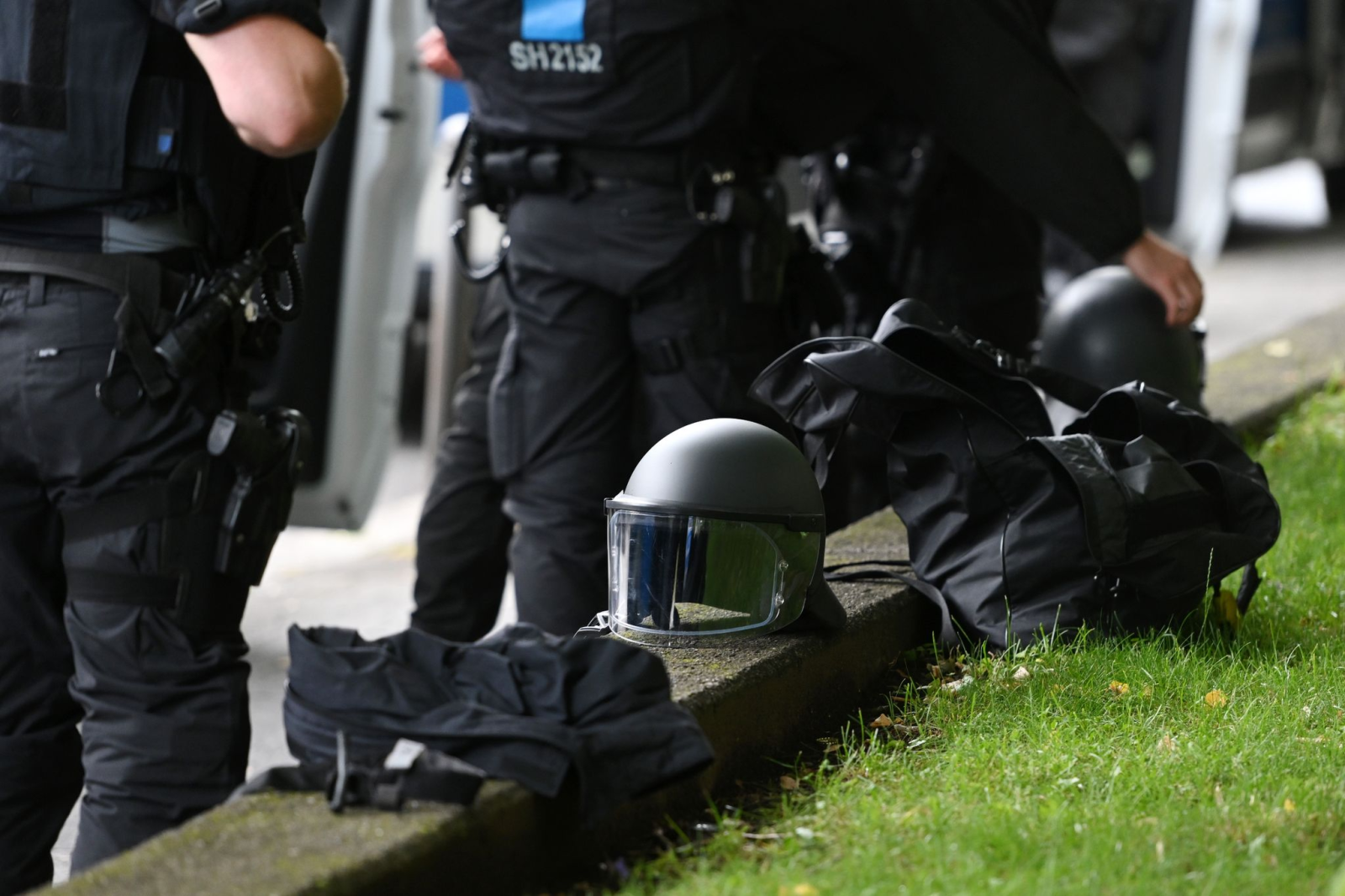 Polizisten haben bei ihren Einsatzfahrzeugen ihre Helme abgelegt.