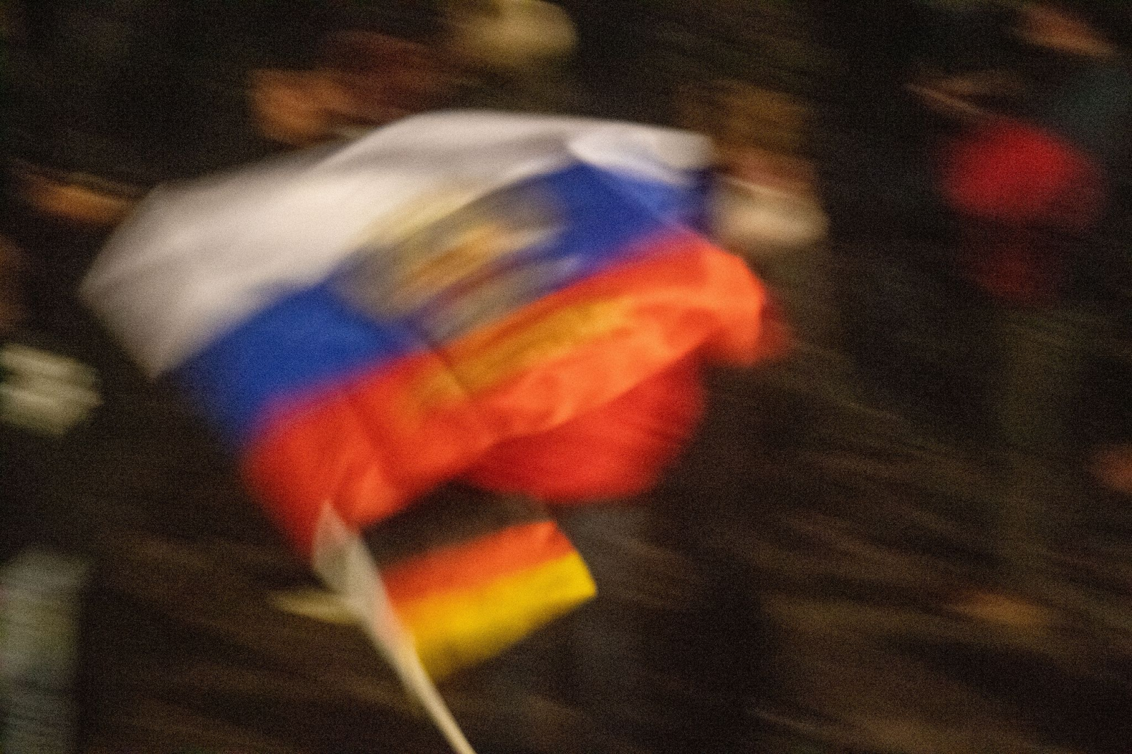 Eine Demonstrantin schwenkt eine russische und eine deutsche Flagge.