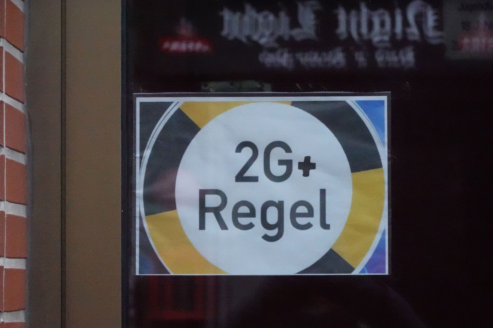 Ein Schild mit der Aufschrift „2G+“ hängt in einem Fenster einer Gaststätte.
