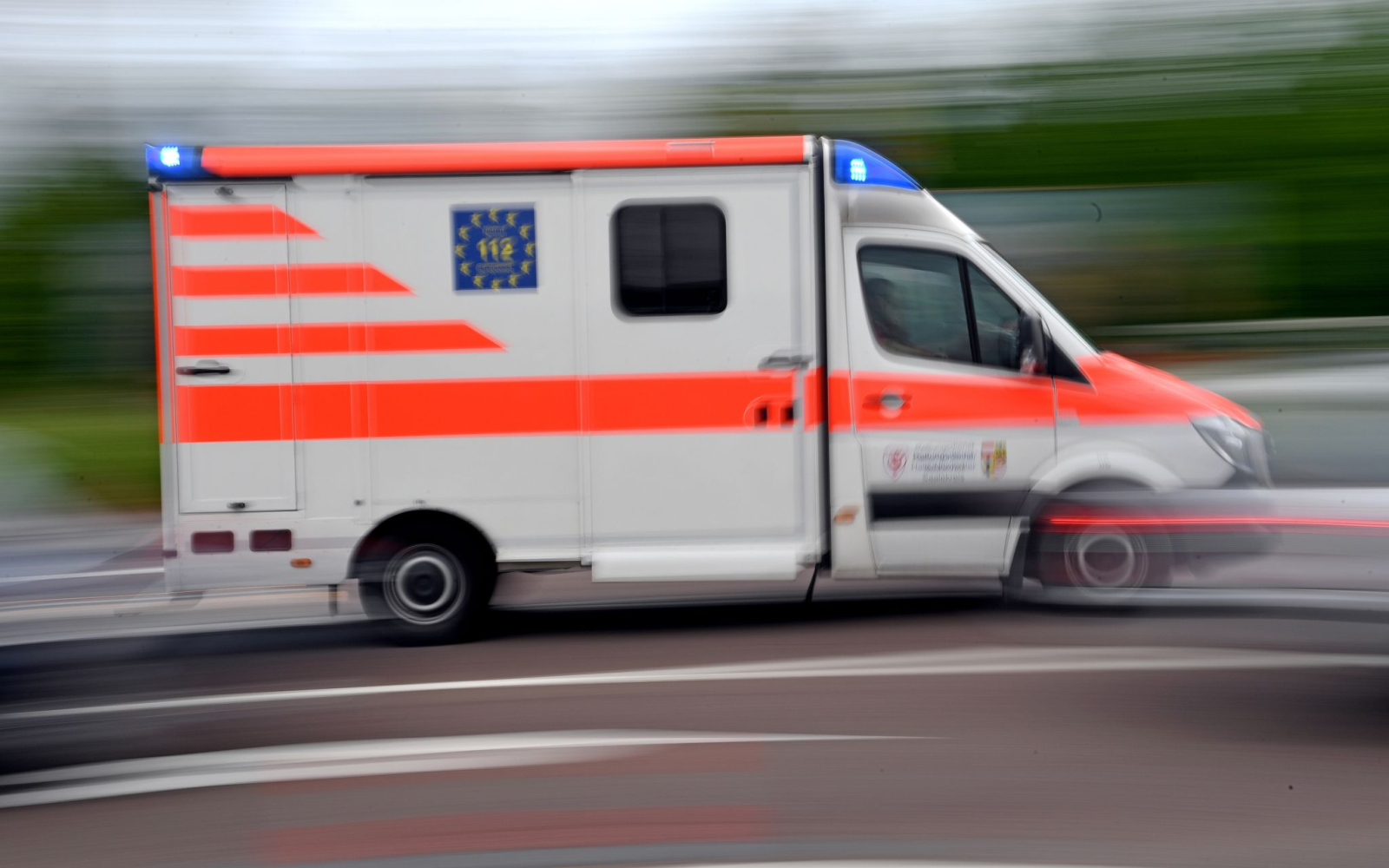 Ein Krankenwagen fährt mit Blaulicht auf einer Straße.