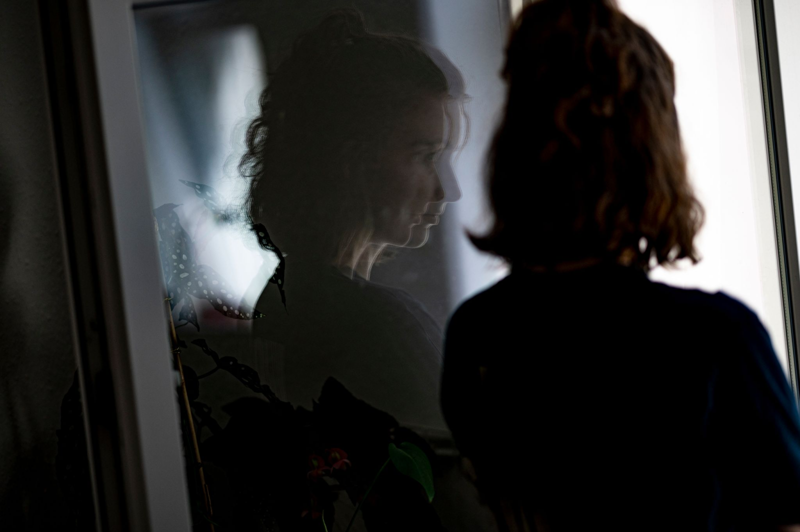 Eine junge Frau in Quarantäne steht am Fenster.