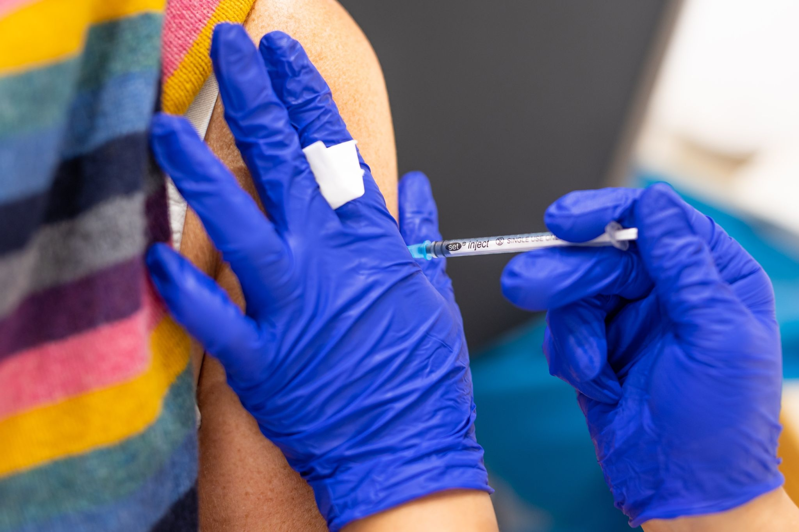 Die Mitarbeiterin eines Impfzentrums impft eine Frau gegen Corona.