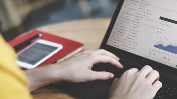 Hände auf dem Laptop daneben ein rotes Notizbuch und ein Handy dadrauf, © Shutterstock Hände auf dem Laptop daneben ein rotes Notizbuch und ein Handy dadrauf, © Shutterstock