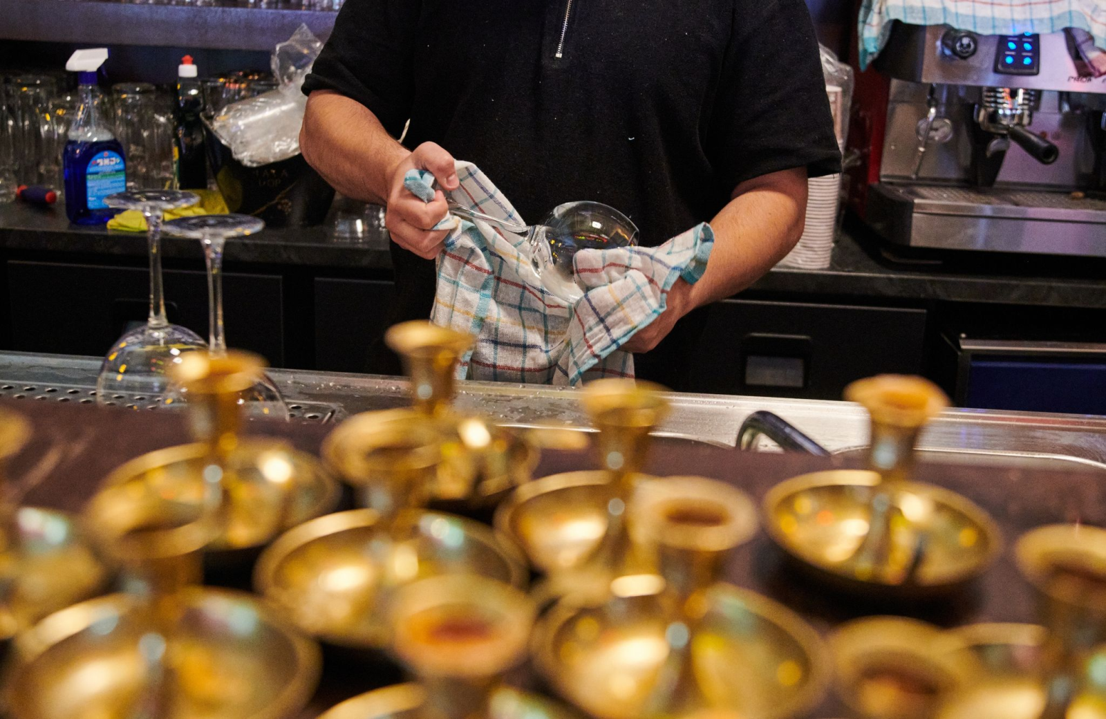 Ein Mitarbeiter eines Restaurants poliert die Weingläser.