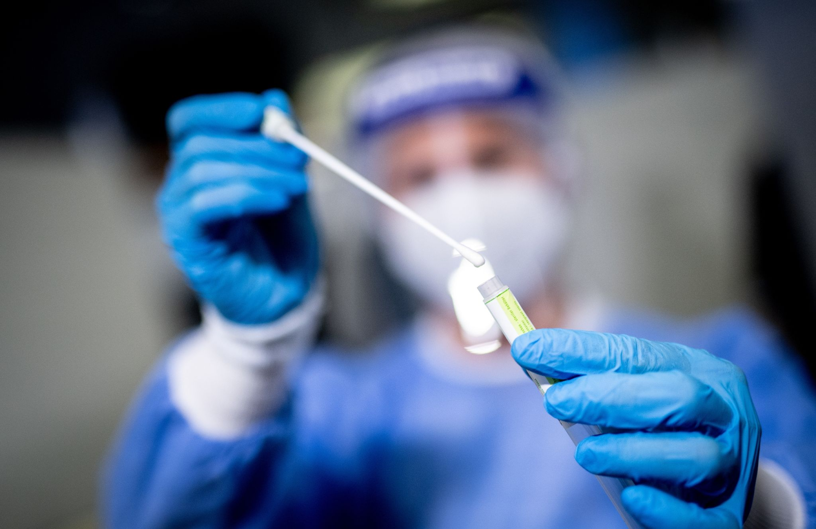 Eine medizinische Mitarbeiterin hält in einem Corona-Testzentrum ein Abstrichstäbchen in der Hand.