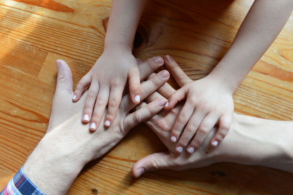 Die Hände eines Paares und eines Kindes liegen zusammen übereinander.