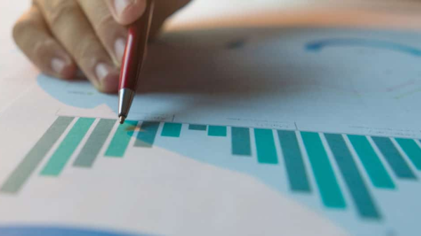 Stift in der Hand deutet auf ausgedruckte Grafiken, © Shutterstock