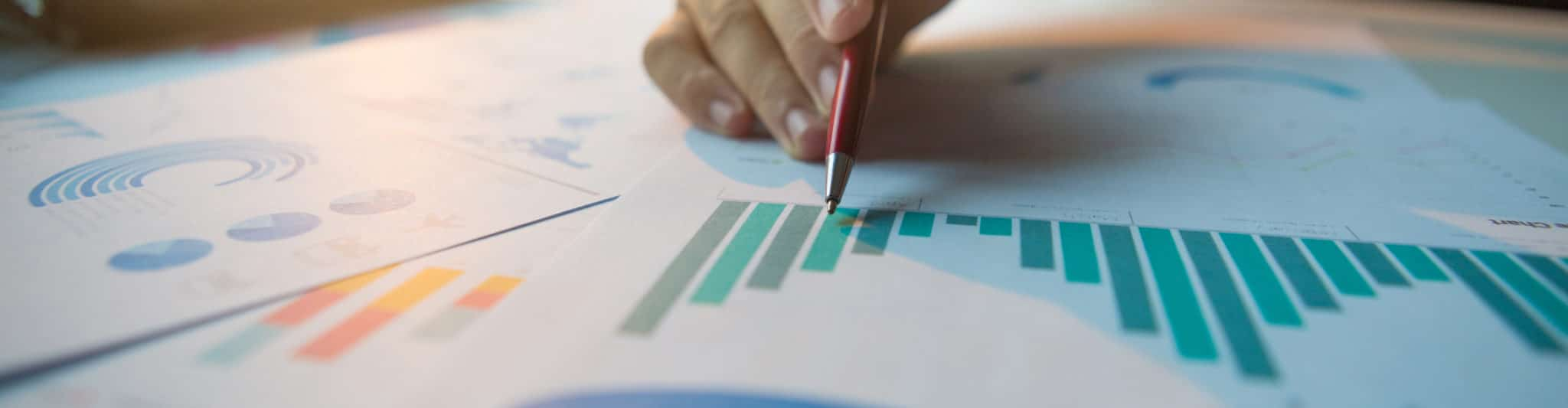 Stift in der Hand deutet auf ausgedruckte Grafiken, © Shutterstock