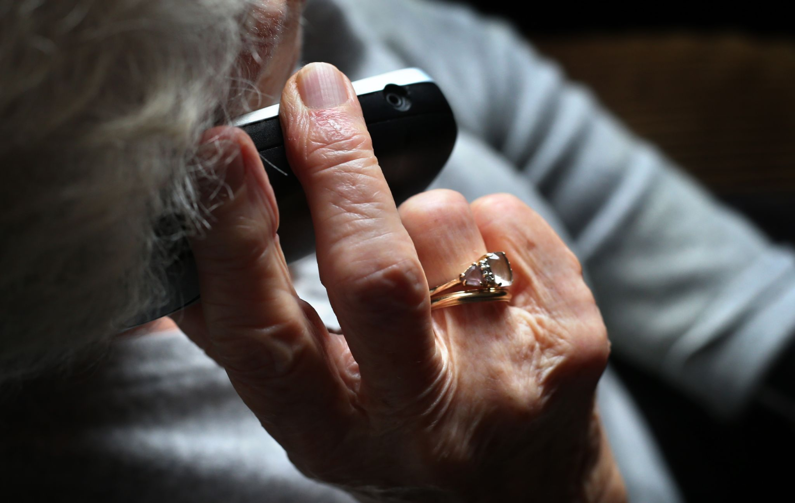 Eine Rentnerin hält ein Telefon in der Hand.