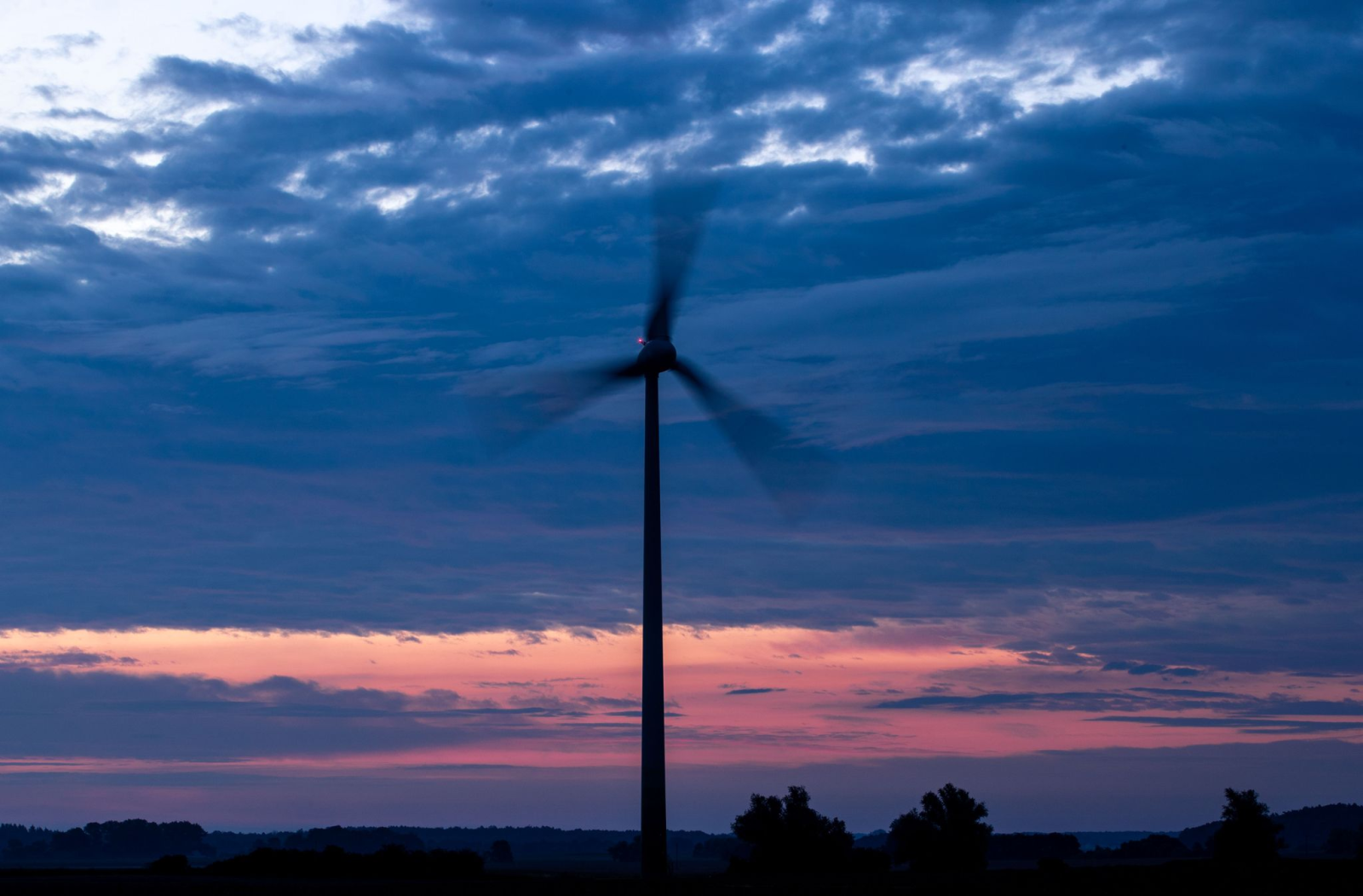 Windkraftanlagen drehen sich vor Sonnenaufgang in einem Windpark.