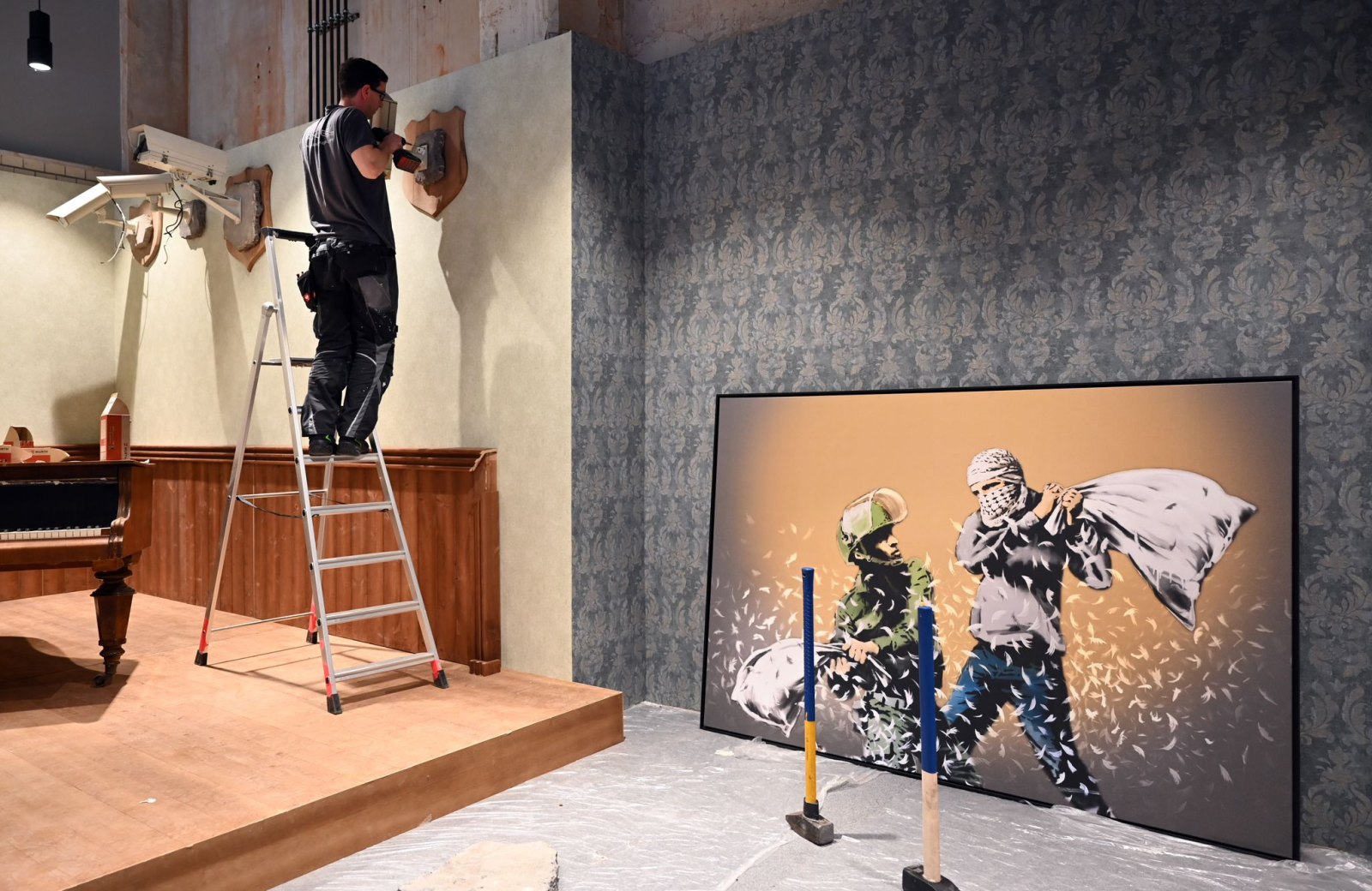 Videokameras werden zur Dekoration neben dem Werk "Pillow Fight" von Banksy angebracht.