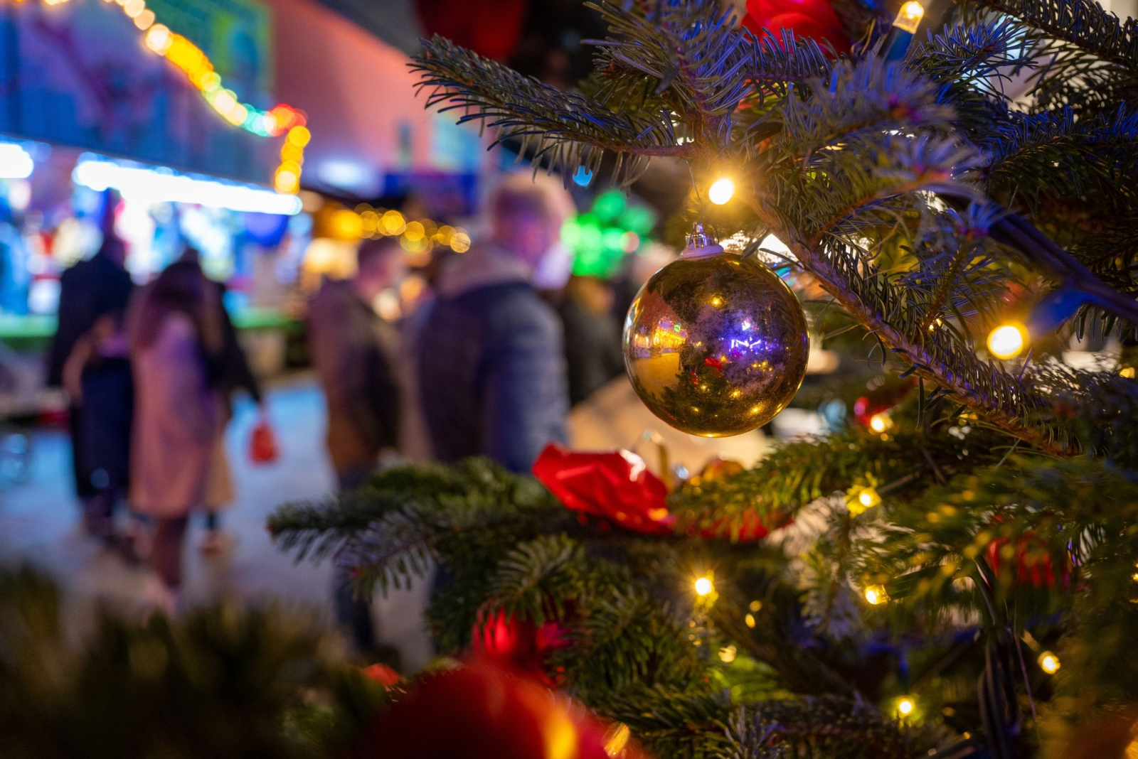 Ein festlich geschmückter Baum steht auf einem Weihnachtsmarkt.