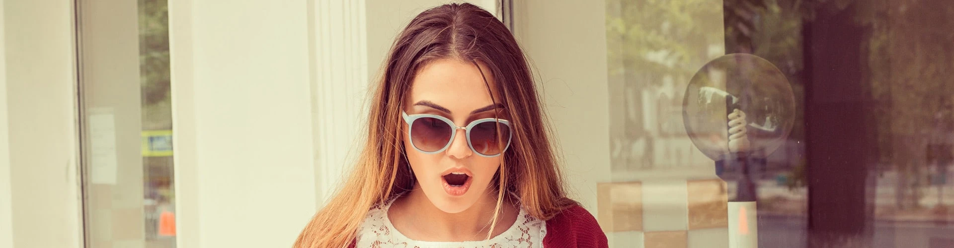 Frau mit Sonnenbrille schaut überrascht mit Mund offen runter, © Shutterstock Frau mit Sonnenbrille schaut überrascht mit Mund offen runter, © Shutterstock